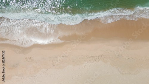 Aerial shot of ocean waves on a sandy beach in Portugal.