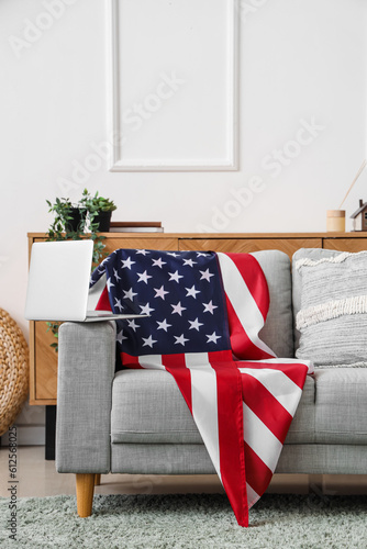 Sofa with USA flag and laptop in interior of living room © Pixel-Shot