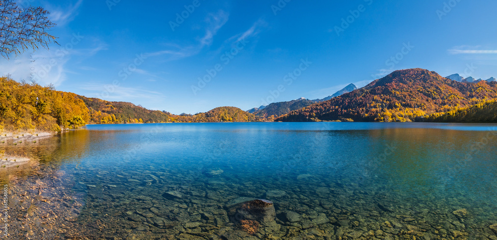 beautiful fairytale landscape in autumn with mountains in the background and a blue lake with the sky