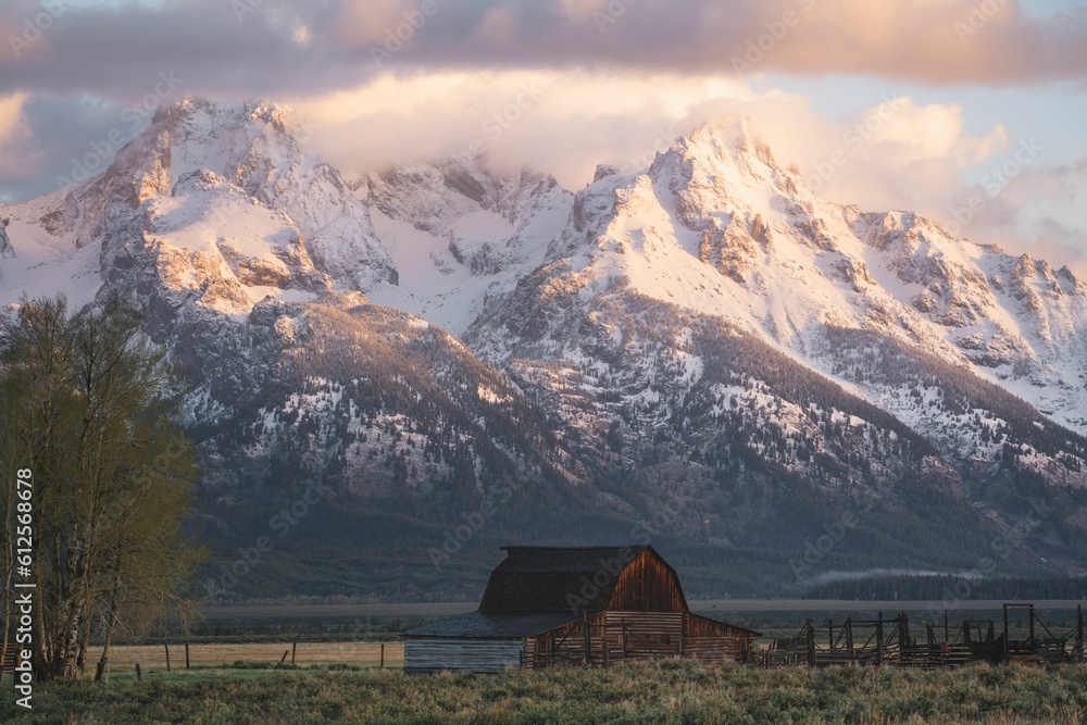 Small hut with the snowy peaks of the Grand Tetons mountains in the background during the daytime