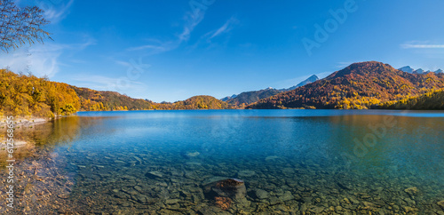 beautiful fairytale landscape in autumn with mountains in the background and a blue lake with the sky