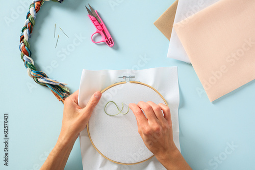 Quadro em tela Female hands embroider on blank canvas, top view