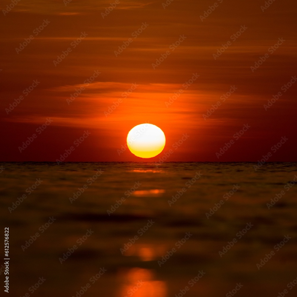 Image of a sun above a water surface during a golden hour Image of a sun above a water surface during a golden hour