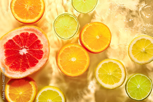 Different citrus fruit slices in water on yellow background