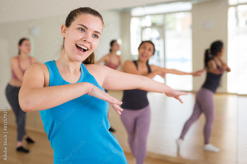 Portrait of young smiling european woman and people dancing in modern studio
