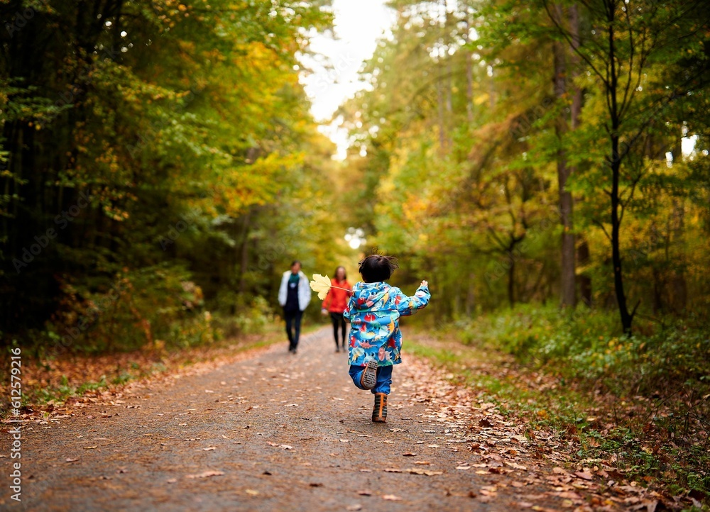 Little boy running towards family in autumn forest Little boy running towards family in autumn forest