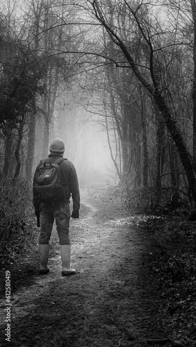 Grayscale of a young male walking through a forest path, vertical shot © Rodel Ditchon/Wirestock Creators