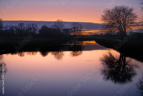 Beautiful landscape with naked trees and their reflection in the lake during sunset