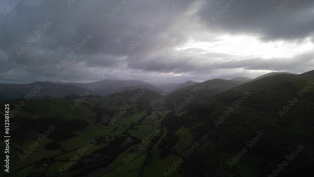 Drone view of a beautiful green countryside against the mountains on a gloomy day