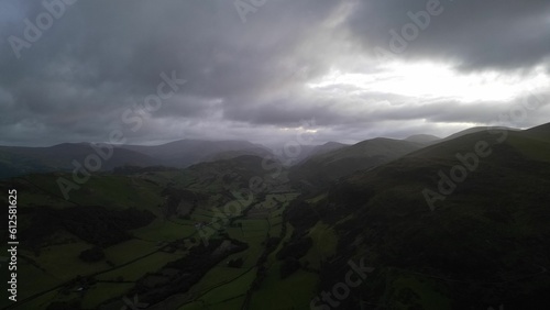 Tablou pe pânză Drone view of a beautiful green countryside against the mountains on a gloomy da
