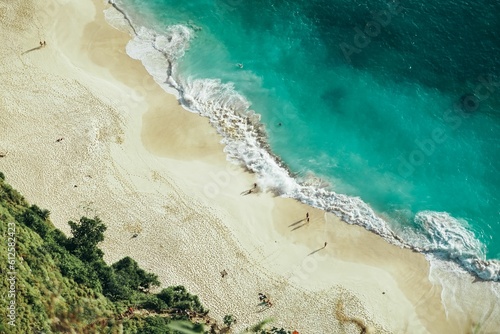 Aerial shot of a beach surrounded by the sea and greenery under the sunlight