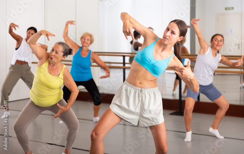 Young dancing woman, engaged in a female group in a modern dance studio, practices energetic swing