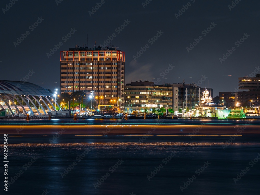 Closeup view of buildings and skyscrapers on the coast of an ocean during nighttime