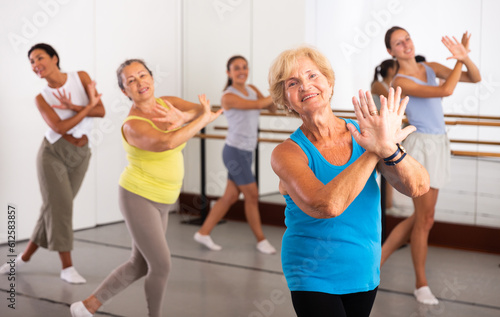 Group of active women practicing energetic dance in a modern dance studio