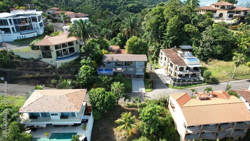 Fototapeta premium Drone view of villas in sunlight surrounded with green trees