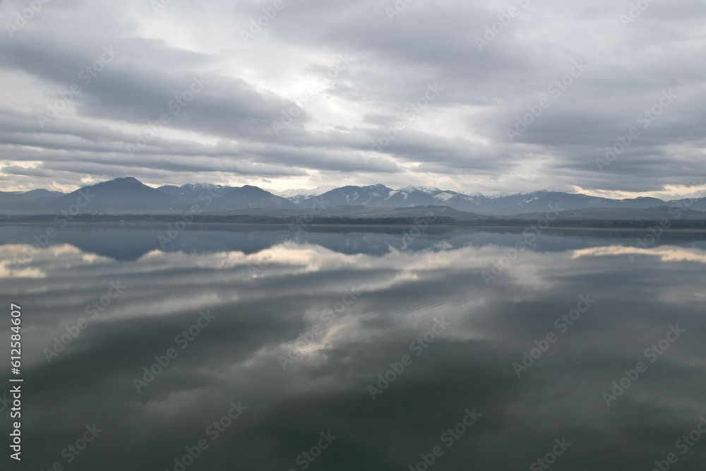 Scenic view of a lake and mountains with the reflection of low clouds on the waters Scenic view of a lake and mountains with the reflection of low clouds on the waters