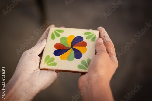 Wallpaper Mural Closeup of dusty human hands holding beautiful square Mexican ceramic tile with floral patterns Torontodigital.ca
