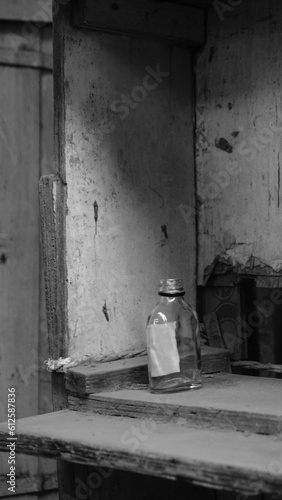 Vertical grayscale shot of an old plastic bottle on a wooden shelf © Siddharth Mehta/Wirestock Creators