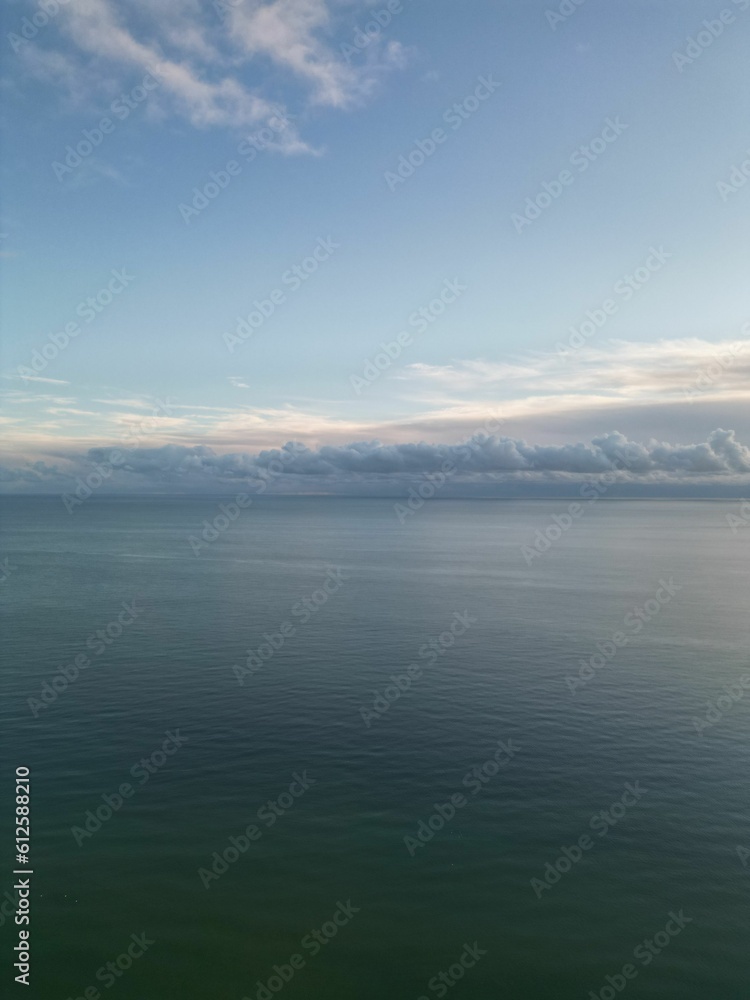 Vertical high-angle of a seascape with beach view with cloudy sky in the background