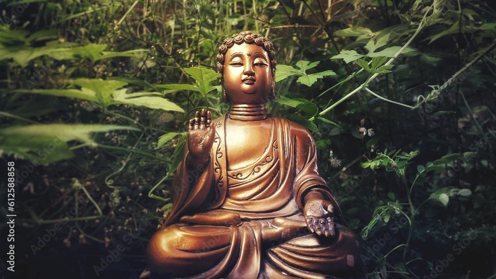 Brown buddha statue in meditation in the forest with green plants in the background