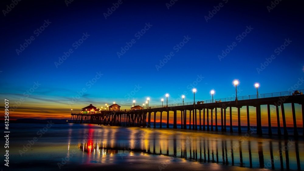 Obraz premium Fantastic view a bright sunset over an oceanside pier with lights