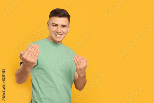 Billede på lærred Handsome man inviting to come in against orange background