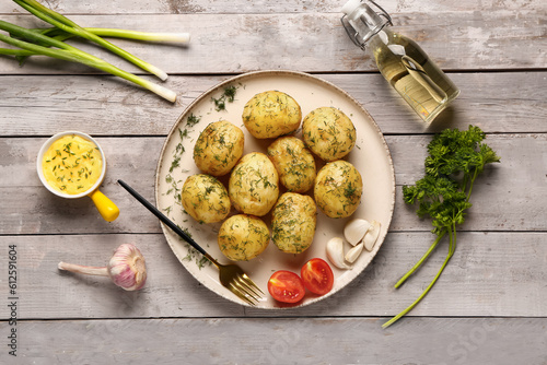 Plate of boiled baby potatoes with dill and tomatoes on grey wooden background