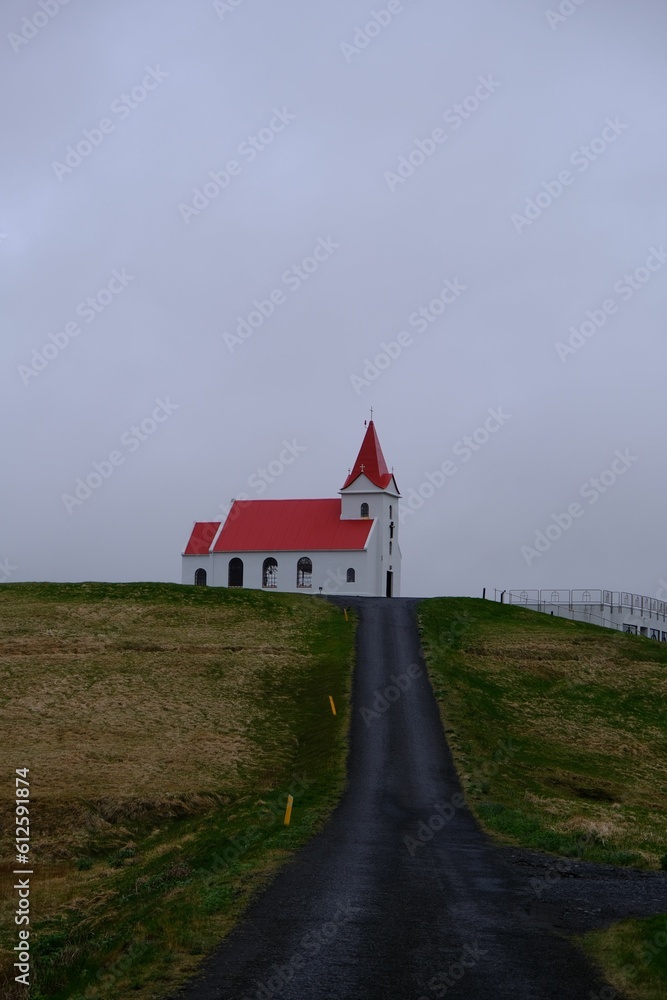 Fototapeta premium Vertical shot of a way leading to Ingjaldsholl church in Iceland under the gloomy sky