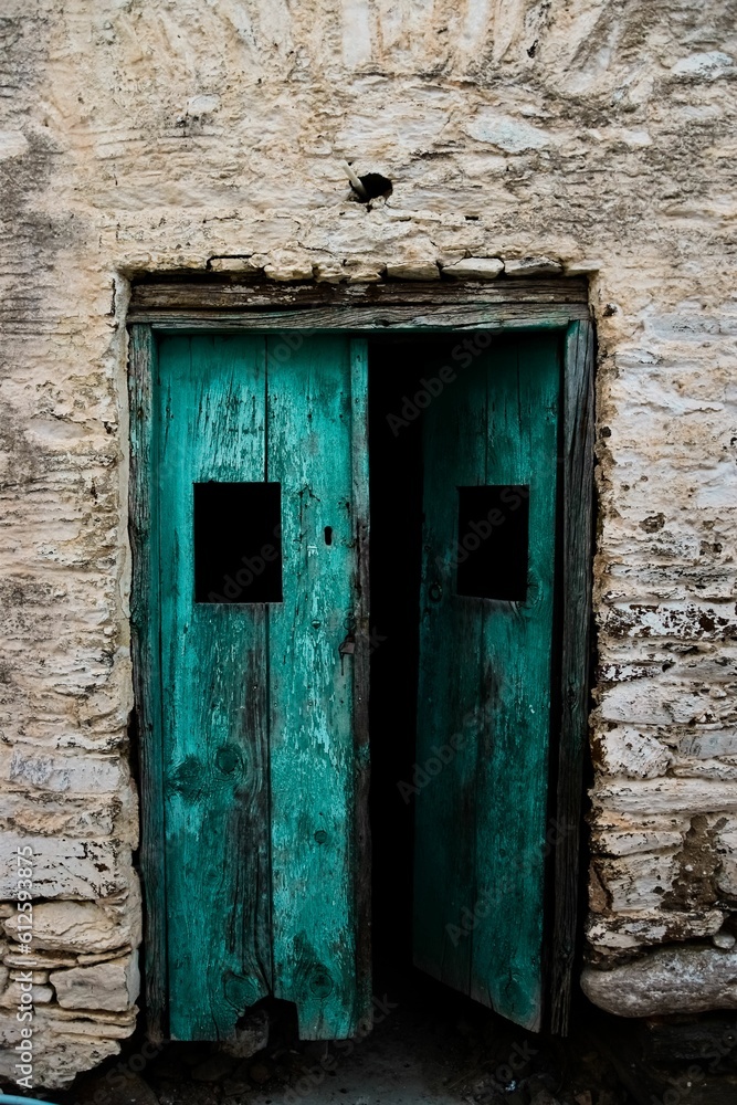 Vertical shot of an ancient wooden door on a stone wall Vertical shot of an ancient wooden door on a stone wall