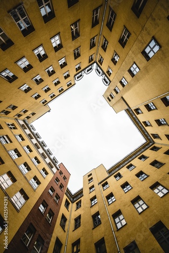 Vertical low-angle shot of the sky seen through yellow tall residential buildings