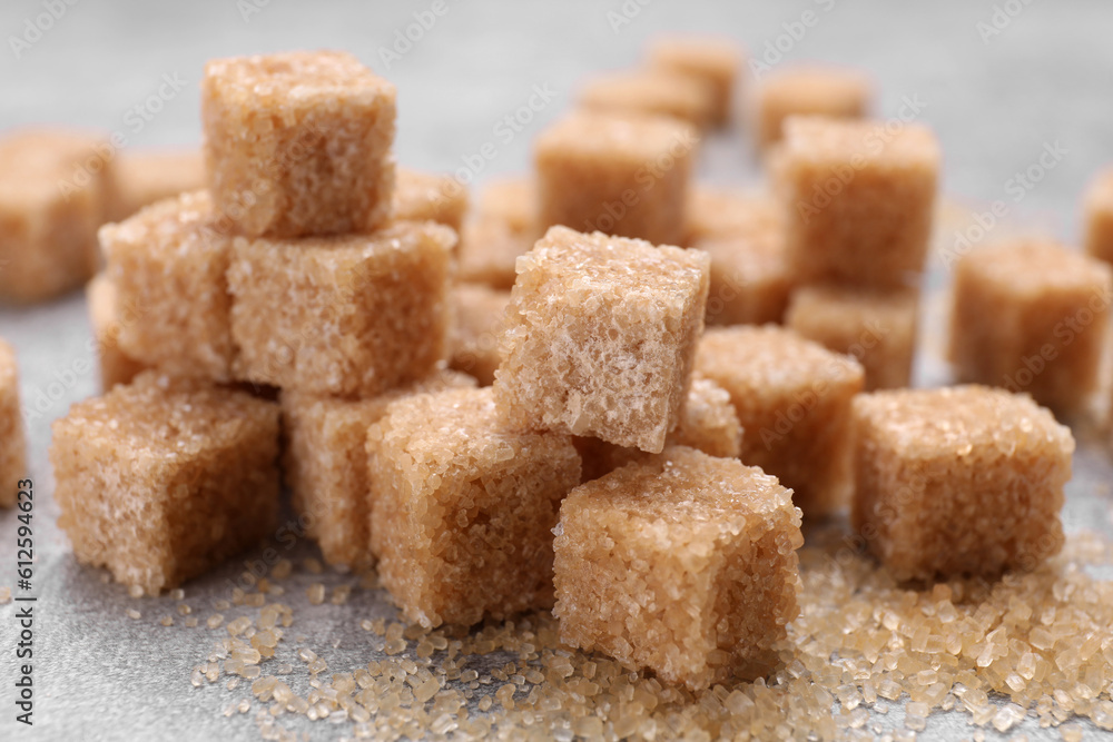 Many brown sugar cubes on grey table, closeup Many brown sugar cubes on grey table, closeup