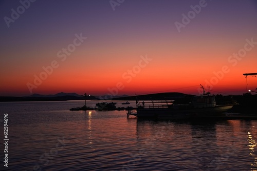 Beautiful shot of a boat silhouette on a pier during a sunset © Spyros P K/Wirestock Creators