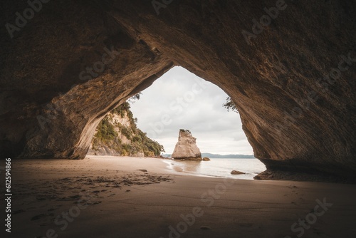 Sandy shore of a sea on an island seen from a cave © Zerlany “zerlany”/Wirestock Creators