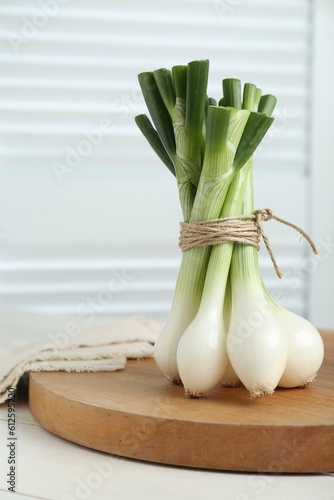 Bunch of green spring onions on white wooden table