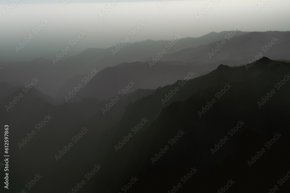 Aerial view of rocky mountains on a foggy day shot in grayscale