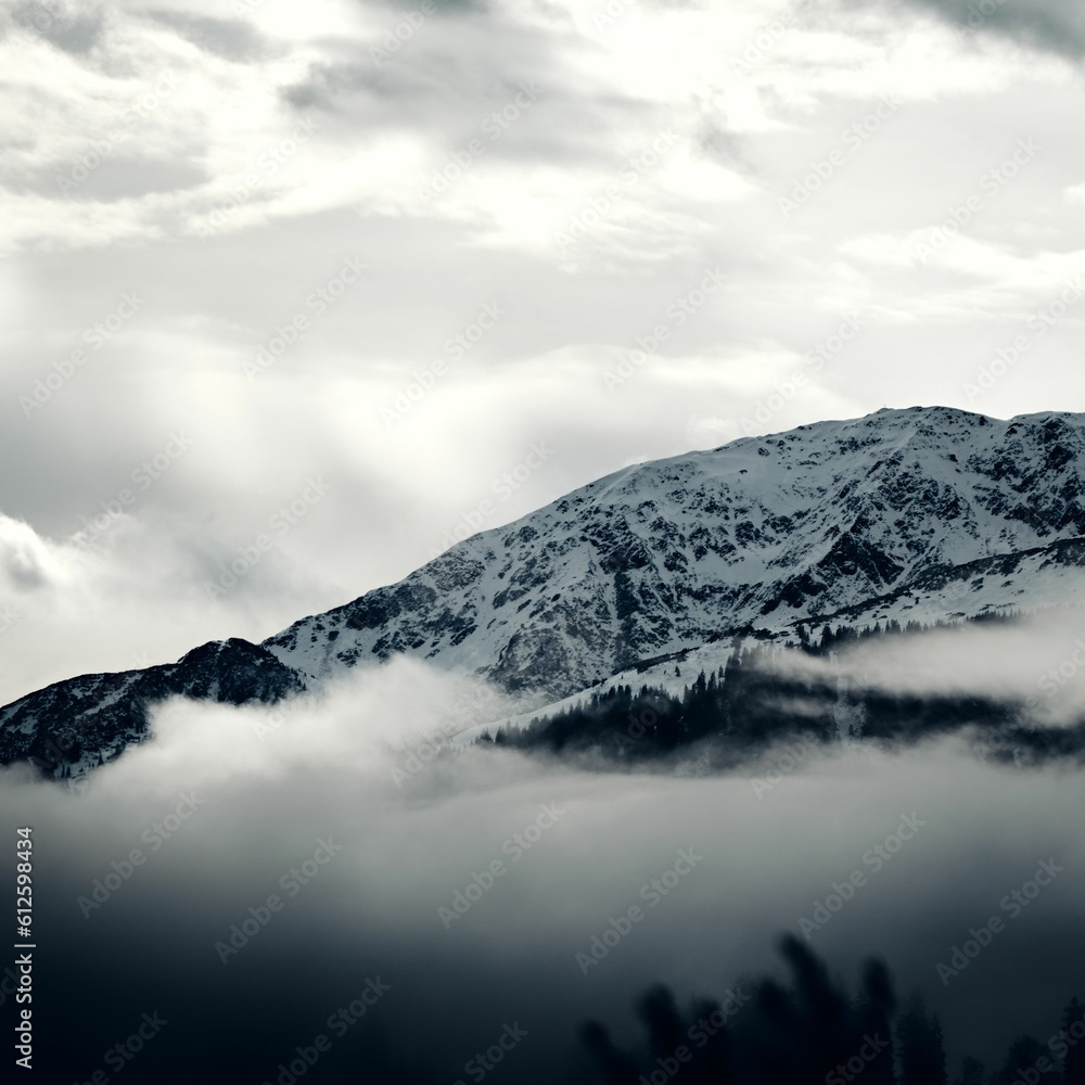 Grayscale view of the snowy Steinbergstein Mountain on a foggy day in the Kitzbuhel Alps, Austria