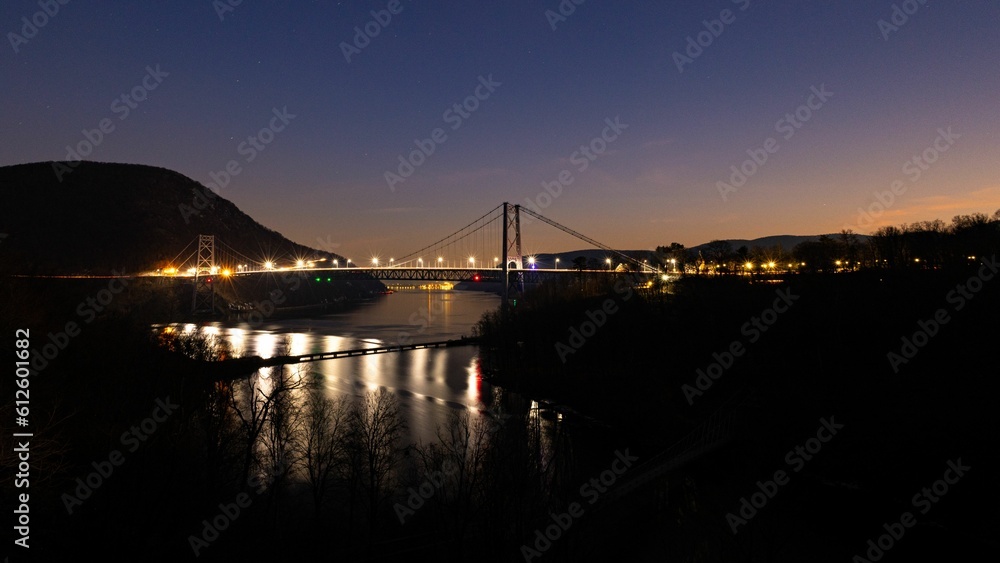 Bear Mountain bridge lit up at night over the river