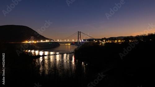 Bear Mountain bridge lit up at night over the river