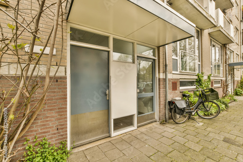 a bike parked in front of a building on the side of a street with trees and bushes growing along it