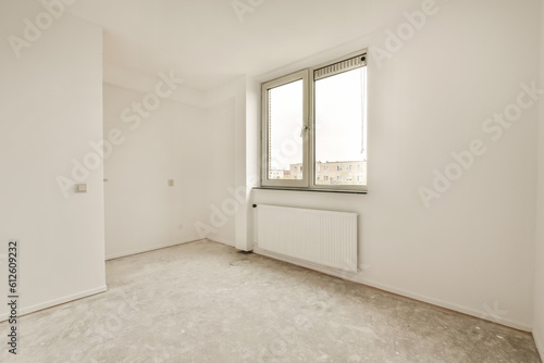 an empty room with white walls and no one person standing in the corner looking out at the view from the window