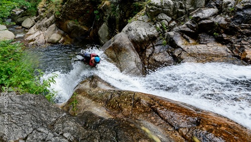 High angle shot of people canyoning through a stream on the side of a mountain in France photo