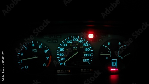 Closeup view of red and blue car speedometers and indicators in the dark of night