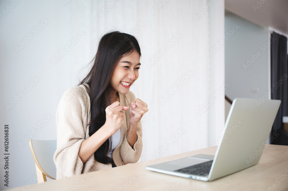 Funny euphoric young asian woman celebrating winning or getting ecommerce shopping offer on computer laptop. Excited happy girl winner looking at notebook celebrating success Funny euphoric young asian woman celebrating winning or getting ecommerce shopping offer on computer laptop. Excited happy girl winner looking at notebook celebrating success