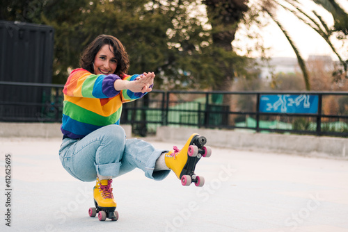 bella mujer latina sonriendo, con frenillos, maquillaje y en patines con polera de arcoíris lgbtq en la calle practicando patinaje photo