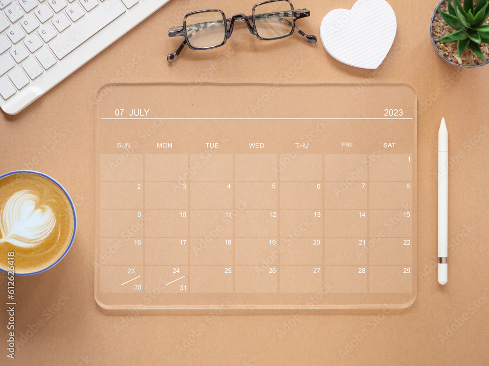 Top view, transparent tablet computer showing July 2023 calendar app ...