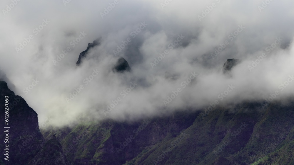 Scenic view of rocky mountains enveloped in white clouds in daylight
