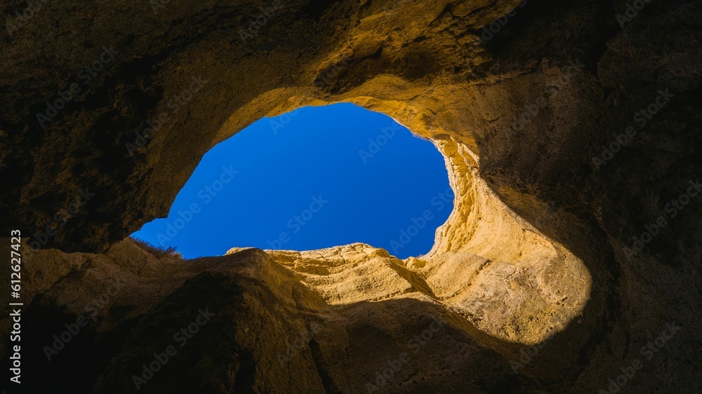 Low-angle view of an opening between the rocks with the blue sky visible from it
