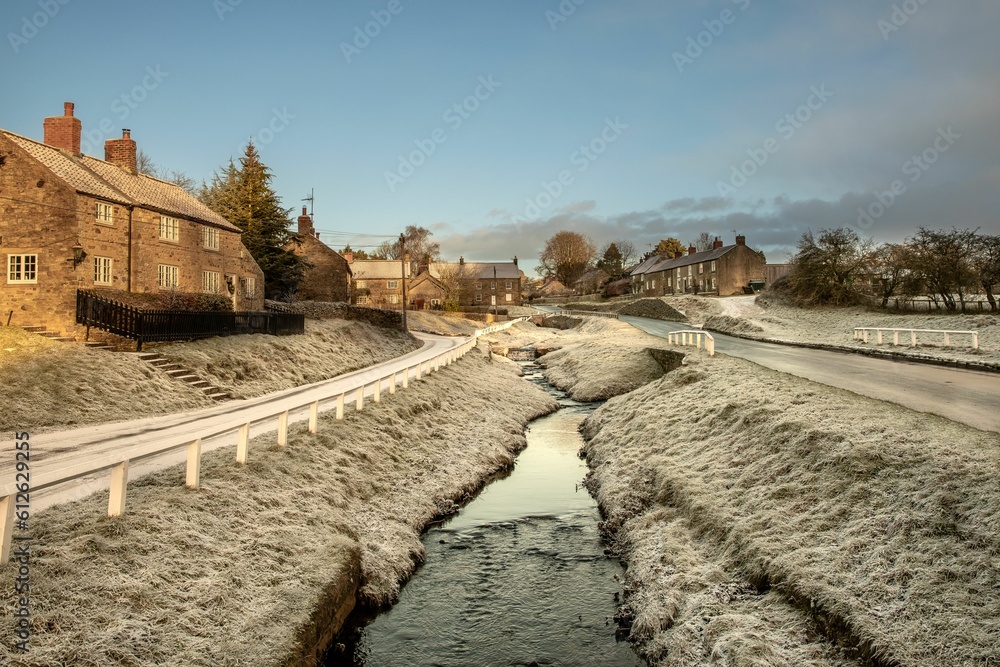 Flowing river surrounded by houses and snow