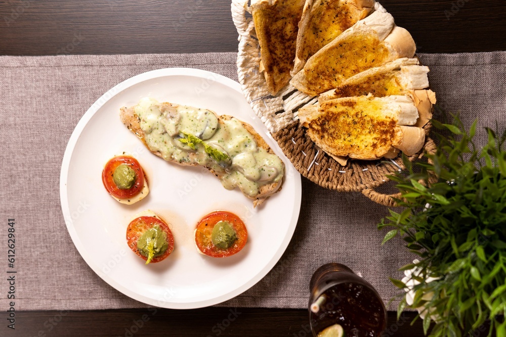 a table topped with a white plate covered in food next to sliced tomatoes a table topped with a white plate covered in food next to sliced tomatoes