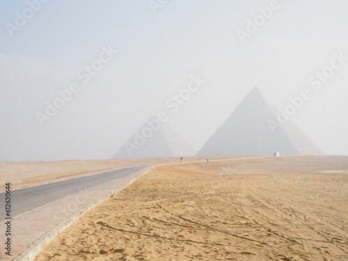 Road through yellow grass leading to the foggy Giza Necropolis museum